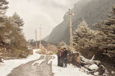 Leh Manali Highway, Hindistan, Aralık 2018 - Turist Grubu Göçebe Banjara Yaya Commuter İnsanlar kış tatilinde Rüzgarlı karlı sisli kaygan çamurlu düz adım himalaya dağ yolu yanında bekliyor.