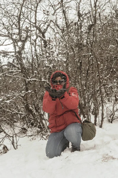 Smiling happy joyful Portrait of a Woman wearing a red pullover jacket enjoying first snow playing and throwing snowball in air. Enjoy Snowing day view in winter. Rural village Jammu and Kashmir India — Stock Photo, Image