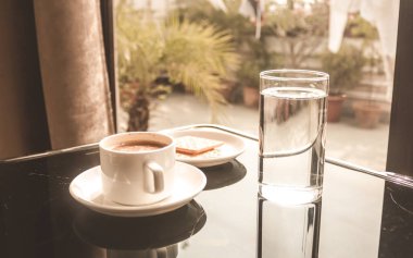 Beyaz kahve fincan yemek masasına yerleştirilen sabah güneş ışığı penceresinden geliyor. Tatlı kokulu sabah kahvesi, Vintage tarzı renk efekti lezzetli bir fincan. Mutlu haftasonu konsepti.