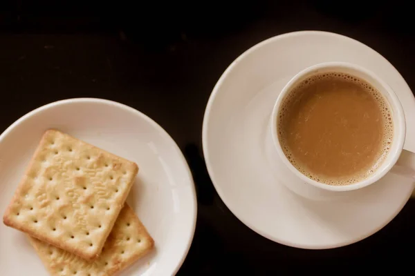 Xícara de chá e prato com pilha de biscoitos de biscoito creme fundo preto isolado. Vista superior. Fecha a imagem. Xícara de chá chinês, biscoitos saborosos. Bebida quente tradicional para o café da manhã. Tônico de ervas . — Fotografia de Stock