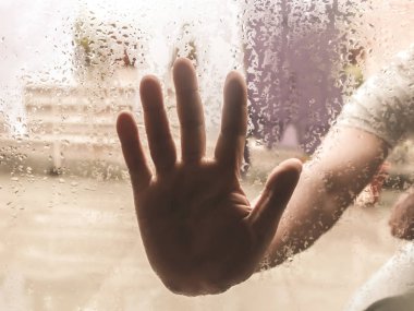 Human Hand pressed against a window with Drops Of Rain on it. Hand touching clear glass with water droplet. Natural Pattern of raindrops isolated from outdoor cloudy environment. clipart