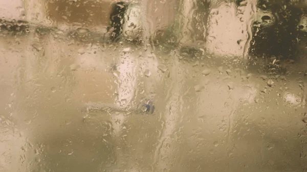 Rain Drops On Surface of wet Window Glass pane In Rainy Season. Abstract background. Natural Pattern of raindrops isolated from blurry city outdoor in a cloudy environment. — Stock Photo, Image
