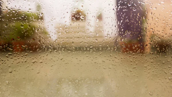 Rain Drops On Surface of wet Window Glass pane In Rainy Season. Abstract background. Natural Pattern of raindrops isolated from blurry city outdoor in a cloudy environment. — Stock Photo, Image