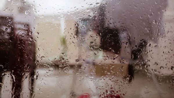 Rain Drops On Surface of wet Window Glass pane In Rainy Season. Abstract background. Natural Pattern of raindrops isolated from blurry city outdoor in a cloudy environment. — Stock Photo, Image