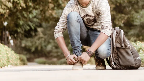 Close up Cropped image of young sportsman athlete man in sports clothing sitting on track and field near playground and tie shoe lace while returning after training jogging or warm up exercise at morn — Stock Photo, Image