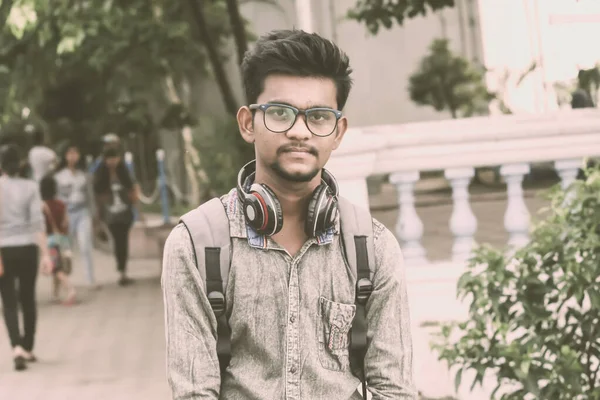 Half length portrait of attractive young a man called Ahok standing outdoors with modern headphones and looking at camera. A music student portrait photography on 21 June, World Music Day. — Stock Photo, Image