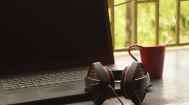 Bilgisayar için Mikrofon Gürültüsü İptal ve Ultrasonik Ses Ayarlayıcı Kulaklık ile taşınabilir Binaural Sound USB kulaklığı, Skype sabahleyin pencere güneşinin yanına dizüstü bilgisayar yerleştirdi. Uzaktan bir fincan kırmızı kahve..