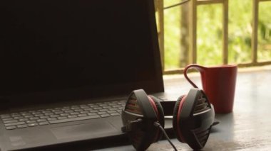 Bilgisayar için mikrofon ultrasonik ses ayarlayıcı kulaklık ile taşınabilir Binaural Sound USB kulaklığı, Skype sabahleyin laptop güneş ışığının yanına yerleştirildi. Uzaktan bir fincan kırmızı kahve. Evde kal, evden çalış, uzaktan çalış, iş devamlılığı