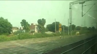 Yüksek hızlı süper hızlı tren Hint tren istasyonundan geçiyor. Pencere kenarı manzaralı tren yolculuğu. Gatimaan Ekspresi 'nde saatte 160 km hızla koşarken dışarıdaki tren penceresine bakıyorsun..