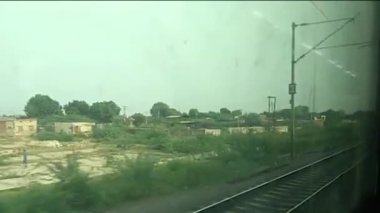 Pencere kenarı manzarasında güzel bir Hint treni yolculuğu. Gatimaan Ekspresi 'nde saatte 160 km hızla koşarken dışarıdaki tren penceresine bakıyorsun..