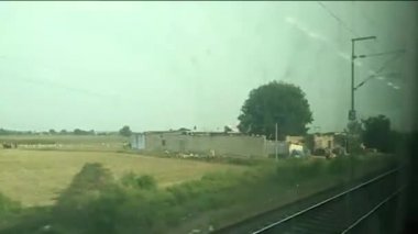 Pencere kenarı manzarasında güzel bir Hint treni yolculuğu. Gatimaan Ekspresi 'nde saatte 160 km hızla koşarken dışarıdaki tren penceresine bakıyorsun..