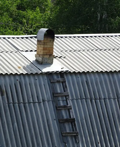 Vieille cheminée rouillée et escalier pourri en bois couché sur un toit carrelé — Photo