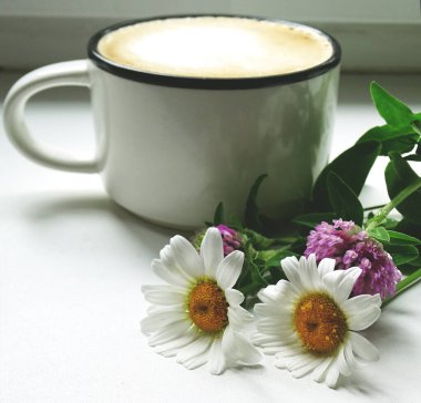 Bir fincan taze kahve ve yabani çiçekler.