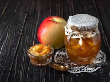 Reçel ve elma ve siyah ahşap bir masa üzerinde bir kaşık ile elma reçel kavanozu ile küçük çanak