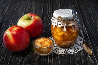 Reçel ve elma ve siyah ahşap bir masa üzerinde bir kaşık ile elma reçel kavanozu ile küçük çanak