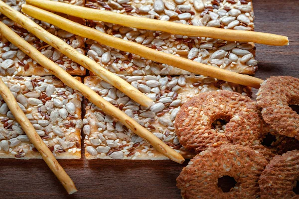 亜麻とゴマひまわりとサクサク ビスケット クラッカーは木製の背景にシードを与えます セレクティブ フォーカス 健康的な食事の概念 — ストック写真
