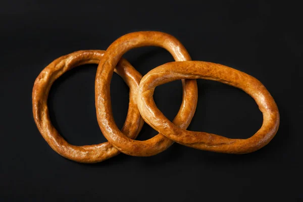 Bolsas en negro. Anillos de pan seco, galletas saladas sobre un fondo negro . —  Fotos de Stock