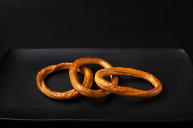 Simit siyah bir plaka üzerinde. Kuru ekmek halkaları, siyah bir arka plan üzerinde kraker. Kopya alanı.