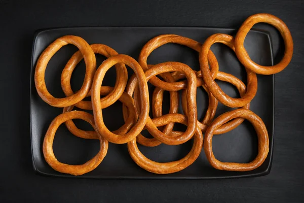 A fekete tányér bagel. Száraz kenyér gyűrűk, kekszek (krekkerek), a fekete lemez. — Stock Fotó