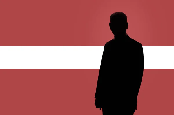 Silhouette di uomo d'affari sullo sfondo della bandiera lettone. Silhouette di un uomo, con spazio per il testo . — Foto Stock