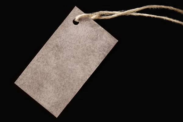 Blank label on a black background, tag attached to the product rope, shows the price or discount — Stock Photo, Image