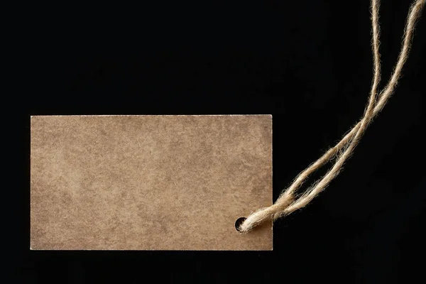 Blank label on a black background, tag attached to the product r — Stock Photo, Image