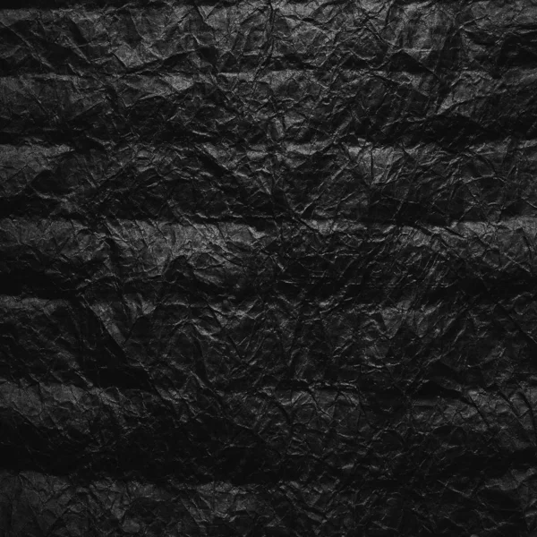 Crumpled black kraft paper. Texture of crumpled black recycled paper. The concept of recycling and reuse of paper and garbage.