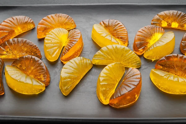 Muchos caramelos cítricos jalea en un plato negro sobre un fondo oscuro . — Foto de Stock