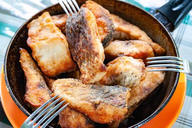 Tavada kızarmış balık ve çatal..