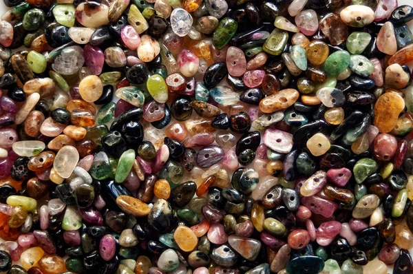 Stone beads from tourmaline background. Close-up of multi-colored beads from natural stone tourmaline. — Stock Photo, Image
