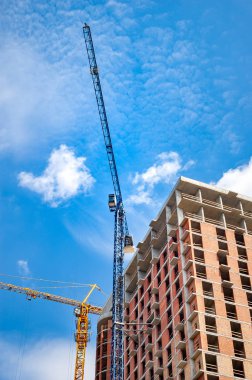 Beyaz bulutlar ile mavi gökyüzüne karşı evin yakınında vinçler ile şantiye. 