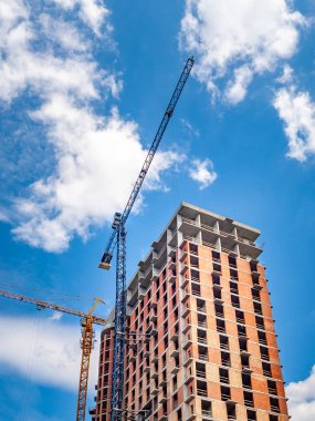 Beyaz bulutlu mavi gökyüzüne karşı vinçler ile şantiye. 