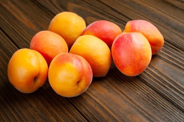 Ahşap bir arka plan üzerinde Ruddy kayısı. Tahta bir masaya yığılmış taze sulu kayısı yığını. 