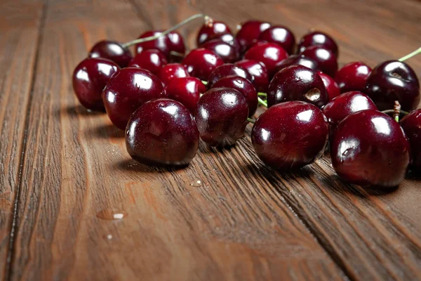 Reife saftige, nasse Süßkirschen auf einem hölzernen Hintergrund. viele nasse frische Kirschen mit Wassertropfen. — Stockfoto