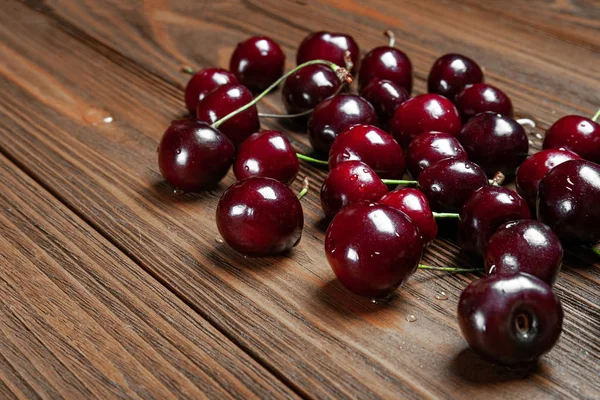 Ripe juicy sweet cherries on a wooden background. Lots of wet fresh cherries with water drops.