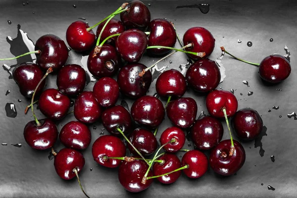 Mouiller les cerises douces juteuses mûres sur une assiette noire. Vue du dessus cerises fraîches humides avec gouttes d'eau . — Photo