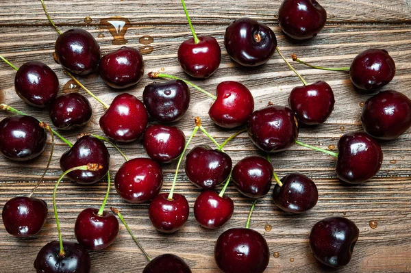 Ripe juicy sweet cherries on a wooden background. Top view wet fresh cherries with water drops.