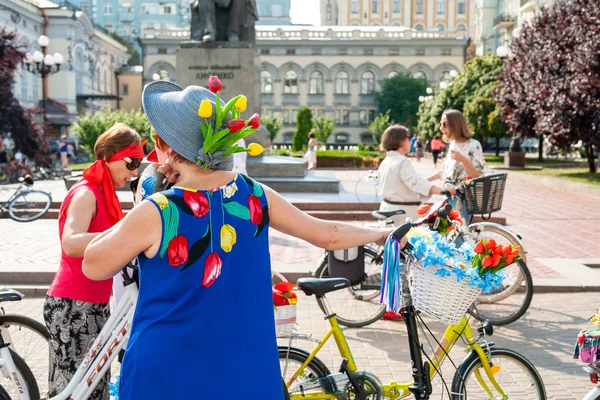 Kijów, Ukraina-27 czerwca 2019: Girls ' Bike show-Kijów Cycle Chic. Kobieta w niebieskiej sukni i kapelusz z kwiatami w pobliżu ozdobiony rower na kobiecej paradzie rowerowej. — Zdjęcie stockowe