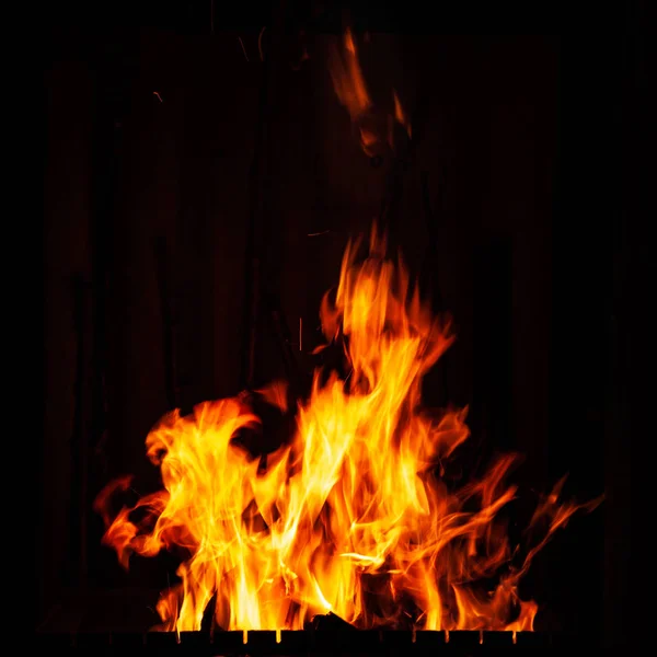 Llama de fuego sobre un fondo negro. Fuego ardiente por la noche. Hoguera en la barbacoa, chimenea y hogar . — Foto de Stock