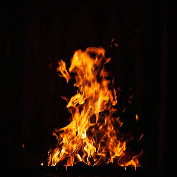 Llama de fuego sobre un fondo oscuro. Quemando fuego en una barbacoa. Hoguera en la barbacoa, chimenea y hogar . — Foto de Stock