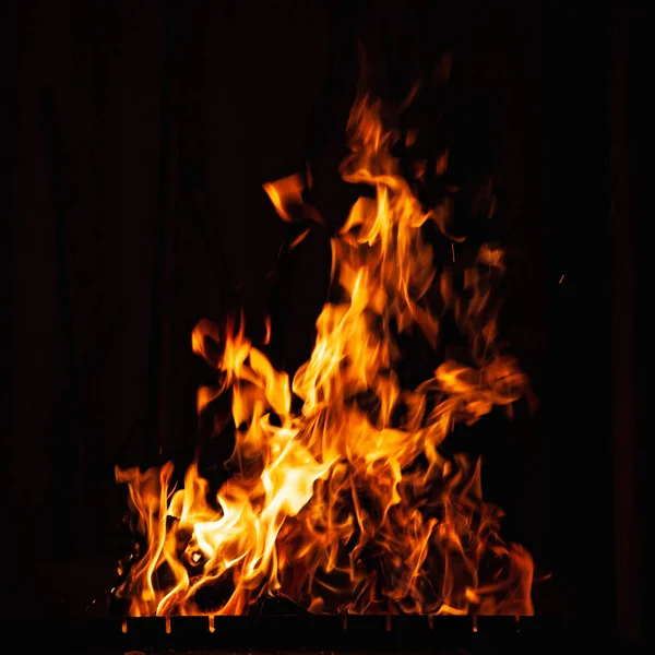 Llama de fuego brillante sobre un fondo oscuro. Fuego ardiente por la noche. Hoguera en la barbacoa, chimenea y hogar . —  Fotos de Stock