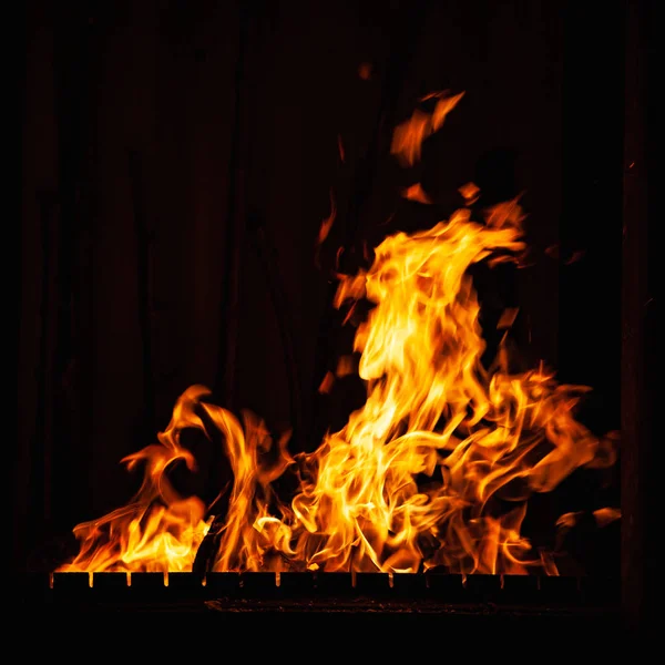 Fire flame on a dark background. Strong burning of fire at night. Bonfire in the barbecue, fireplace and hearth. — Stock Photo, Image