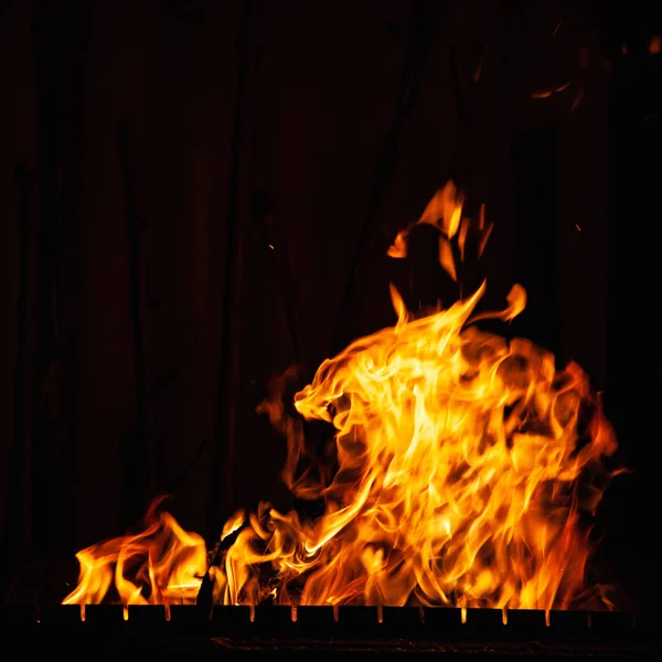 Chama de fogo em um fundo escuro. Fogo a arder à noite. Fogueira brilhante no churrasco, lareira e lareira . — Fotografia de Stock