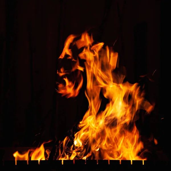 Llama de fuego. Fuerte fuego ardiendo de noche. Hoguera en la barbacoa, chimenea y hogar . — Foto de Stock