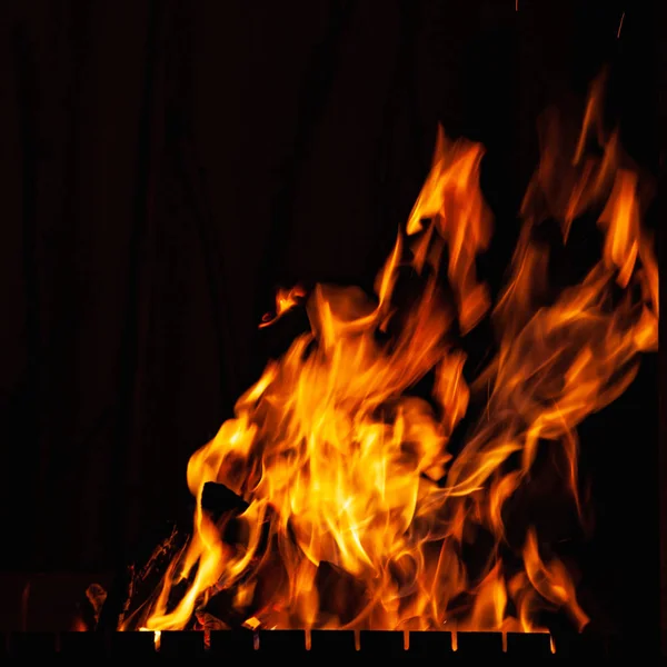 Llama de fuego. Fuerte fuego ardiendo de noche. Un fuego en la parrilla, chimenea y hogar . — Foto de Stock