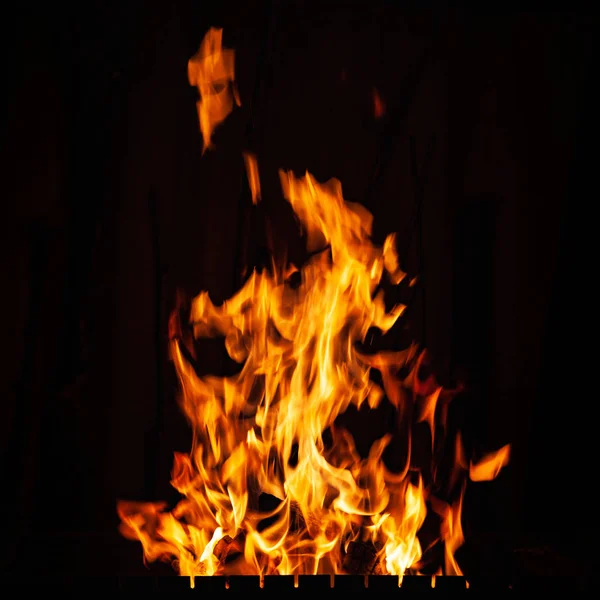 Llamas de fuego. Un fuego en la parrilla, chimenea y hogar. Fuego ardiendo por la noche . — Foto de Stock