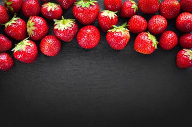 Çilek arka planında mesaj için yer var. Koyu bir taşın üzerinde çilek. Kopya alanı olan arkaplan resmi. Sağlıklı meyveler. Doğal organik gıda..