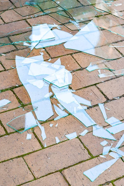 Broken glass. Shards of broken glass on the paving stones. The concept of destruction. Image for editing and design.