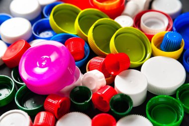 Plastik şişe kapaklarının üst görüntüsü. Geri dönüşümlü plastiğin kapsülleri. Ayrı çöp toplama yeri. Protez için plastik geri dönüşümü. Seçici odaklanma. Çok renkli desen.