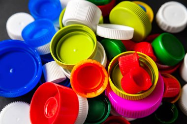 Siyah arka planda renkli PET kapakları. Geri dönüştürülmüş plastik şişe kapakları. Ayrı çöp toplama yeri. Protez için plastik geri dönüşümü. Seçici odaklanma. Çok renkli desen.